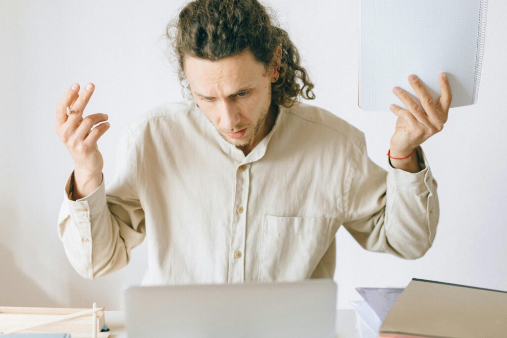 A frustrated man at his desk showing signs of exhaustion and stress in an office setting.