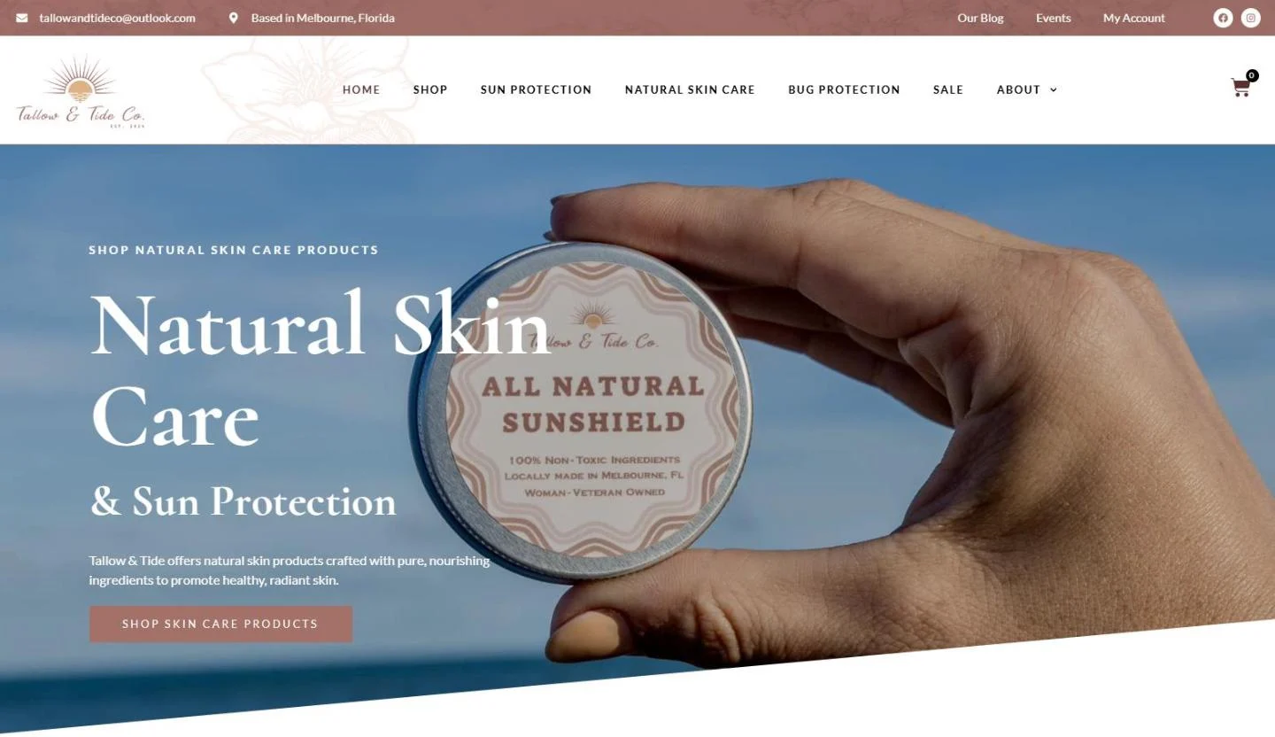 The Tallow and Tide Co. homepage with a hand holding a tin of All Natural Sunshield against a blue ocean sky